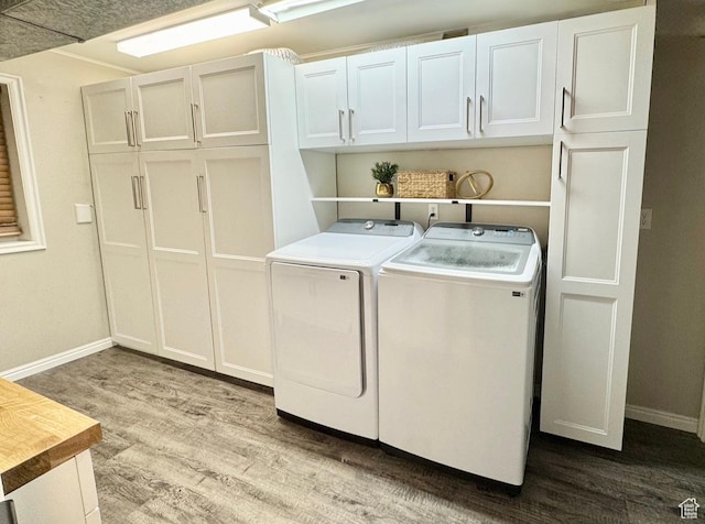 laundry room featuring cabinet space, wood finished floors, baseboards, and washer and dryer