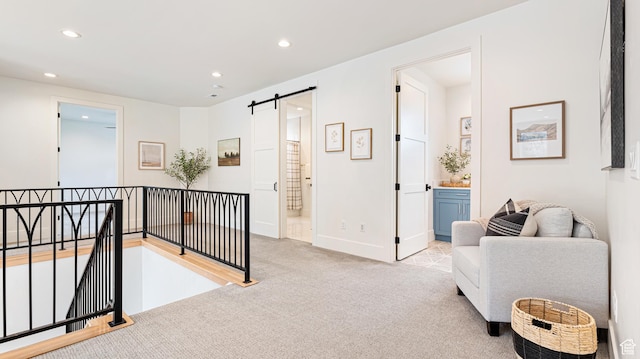 sitting room featuring a barn door, recessed lighting, an upstairs landing, carpet floors, and baseboards