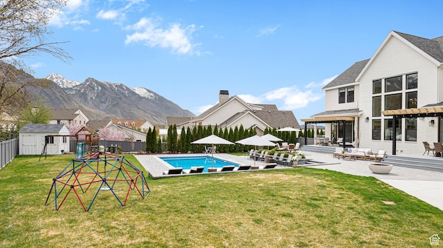 view of swimming pool featuring a fenced in pool, a fenced backyard, a storage shed, a patio area, and an outdoor structure