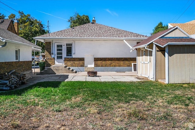back of house featuring a patio area, a lawn, a shingled roof, and stucco siding