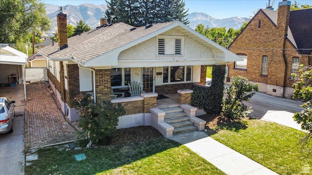 bungalow with a porch, a chimney, a front yard, and a mountain view