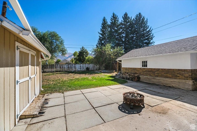 view of patio / terrace featuring a fenced backyard, an outdoor structure, and an outdoor fire pit