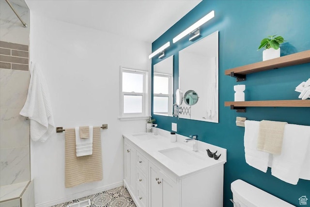bathroom with a sink, baseboards, a shower, double vanity, and toilet