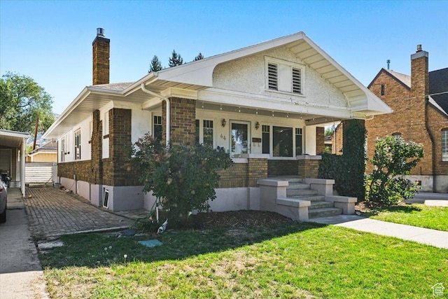 bungalow-style home featuring a porch, a front lawn, and a chimney