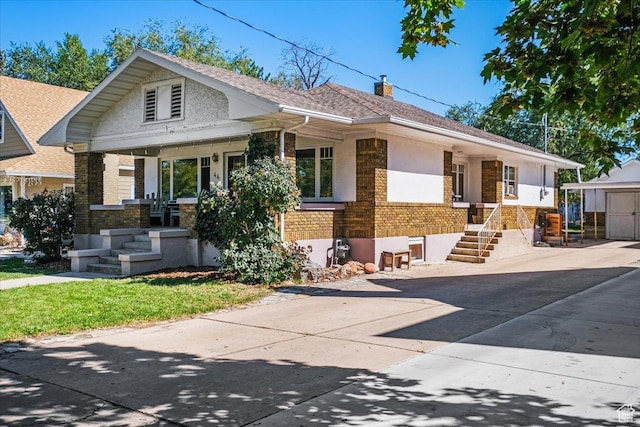 view of front of property featuring a chimney, driveway, covered porch, stucco siding, and brick siding