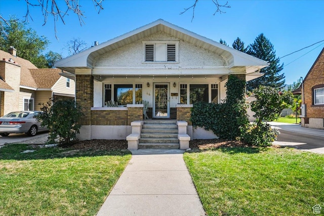 bungalow-style home featuring a front lawn and covered porch
