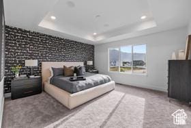 bedroom featuring recessed lighting, a raised ceiling, and an accent wall
