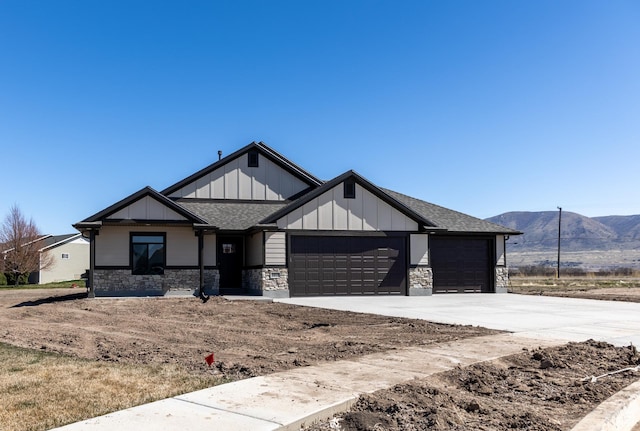 view of front of house featuring an attached garage, a mountain view, stone siding, and board and batten siding