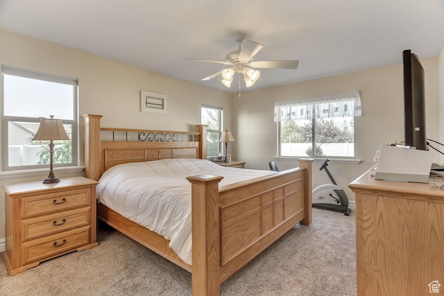 bedroom with ceiling fan, light carpet, and baseboards
