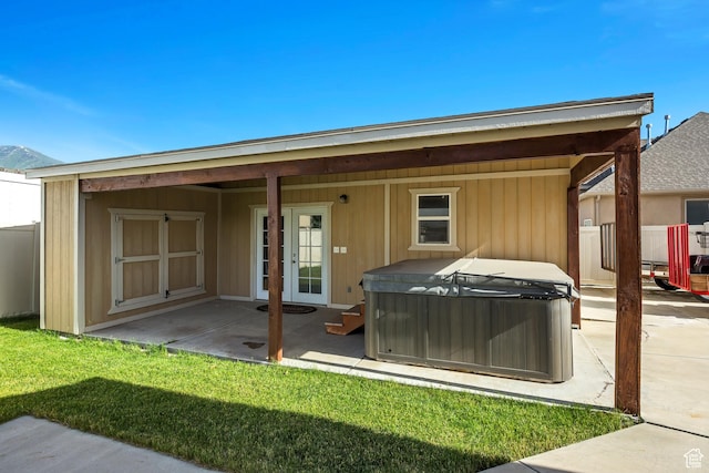 back of property featuring a yard, french doors, a hot tub, and a patio