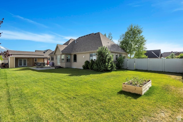 rear view of property featuring french doors, a fenced backyard, a patio area, a vegetable garden, and a yard