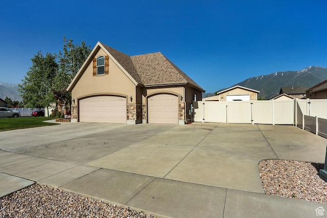 view of front of home featuring a gate, concrete driveway, fence, a mountain view, and stucco siding
