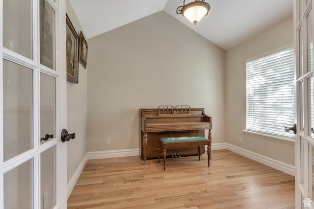 living area featuring light wood-style floors, vaulted ceiling, and baseboards