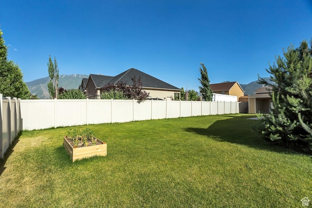 view of yard with a vegetable garden, fence, and a mountain view