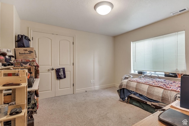 carpeted bedroom featuring baseboards, visible vents, and a closet