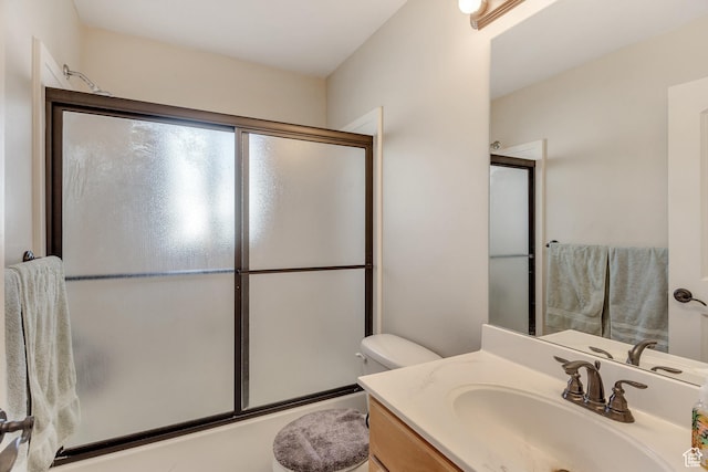 bathroom with vanity, toilet, and bath / shower combo with glass door
