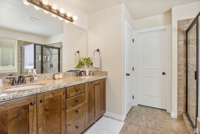 bathroom featuring double vanity, a shower stall, visible vents, and a sink