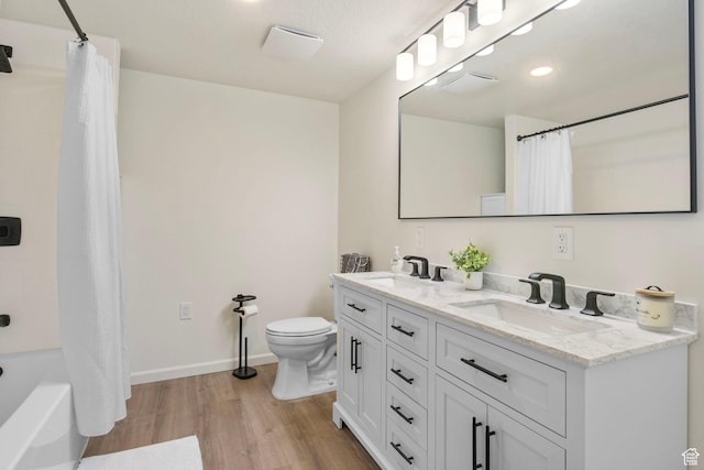 full bath with double vanity, wood finished floors, toilet, and a sink