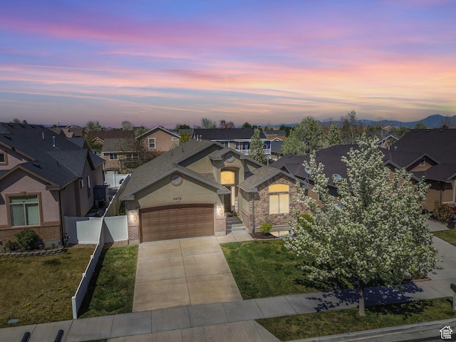 traditional-style home with driveway, fence, a garage, brick siding, and a residential view
