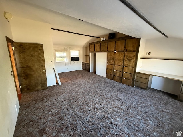unfurnished living room with lofted ceiling, carpet flooring, and built in desk