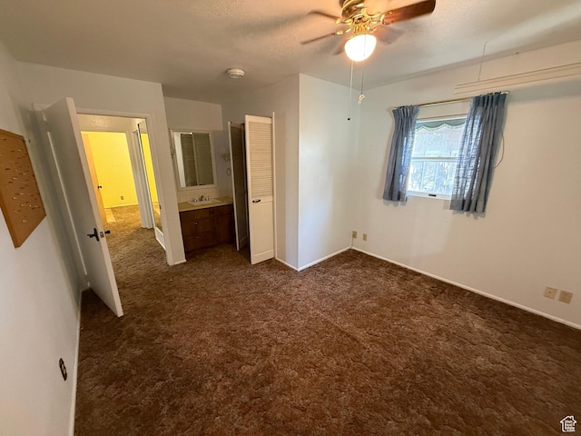 unfurnished bedroom featuring dark colored carpet, baseboards, a sink, and ceiling fan
