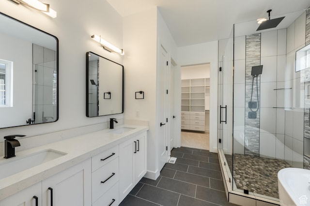full bathroom featuring a shower stall, tile patterned flooring, double vanity, a walk in closet, and baseboards