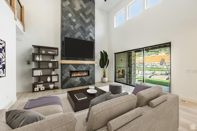 living room featuring wood finished floors, a high ceiling, a fireplace, and baseboards