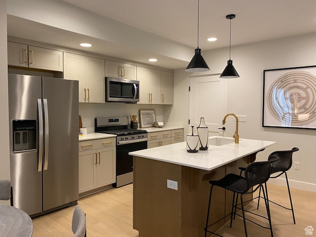 kitchen featuring recessed lighting, a kitchen breakfast bar, stainless steel appliances, a sink, and light wood-style flooring