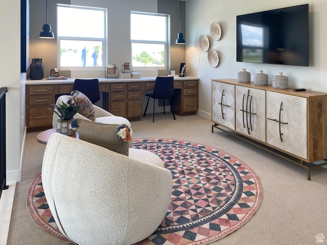 living room featuring built in study area, light carpet, a healthy amount of sunlight, and baseboards