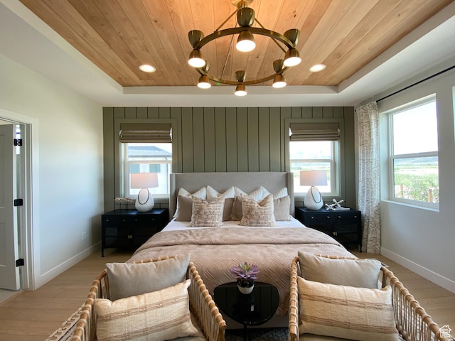 bedroom with baseboards, a raised ceiling, light wood-style flooring, and wood ceiling