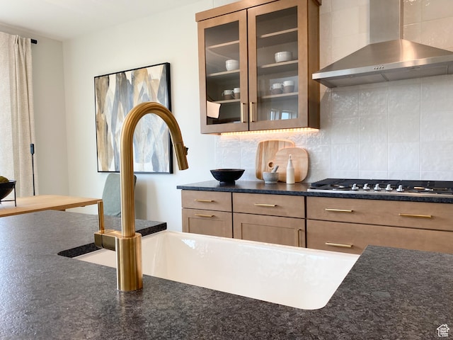 kitchen with stainless steel gas cooktop, wall chimney exhaust hood, decorative backsplash, and a sink