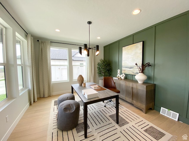 office space with a chandelier, light wood-type flooring, visible vents, and baseboards