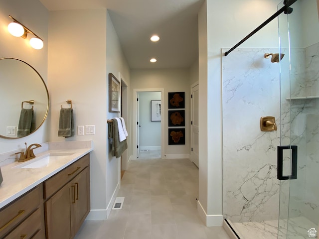 bathroom featuring a marble finish shower, vanity, baseboards, visible vents, and recessed lighting