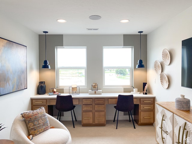 home office with light colored carpet, built in study area, visible vents, and plenty of natural light