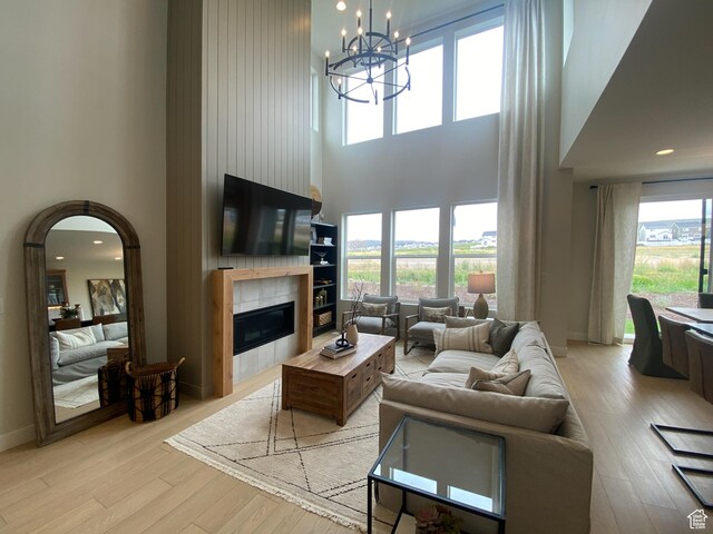 living room with a wealth of natural light, a high ceiling, light wood finished floors, and a fireplace