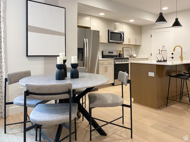 kitchen with recessed lighting, stainless steel appliances, light countertops, light wood-type flooring, and a breakfast bar area