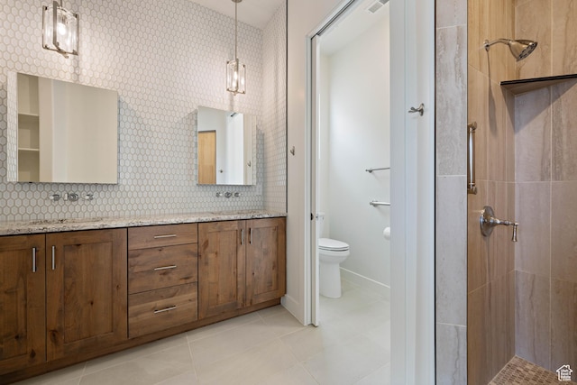 full bathroom featuring a sink, double vanity, tiled shower, toilet, and tile patterned flooring