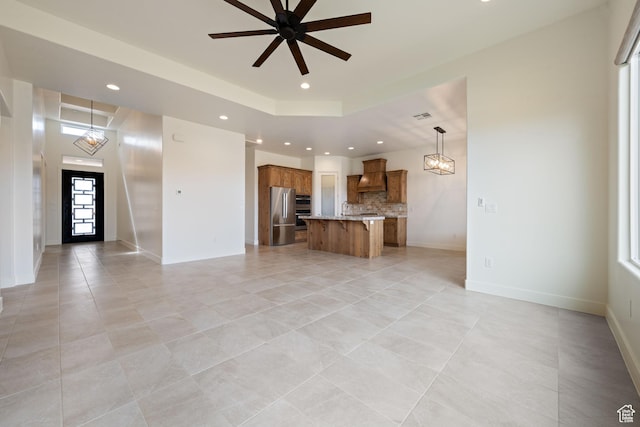 unfurnished living room with baseboards, recessed lighting, light tile patterned floors, and ceiling fan with notable chandelier