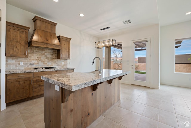 kitchen with custom exhaust hood, tasteful backsplash, a sink, visible vents, and recessed lighting