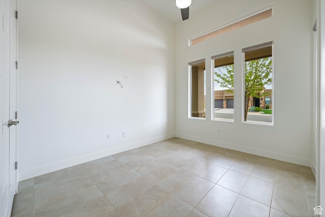 spare room with ceiling fan, baseboards, and light tile patterned floors