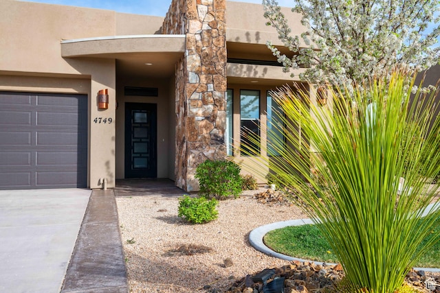 entrance to property with a garage and stucco siding