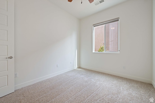 carpeted empty room with baseboards, a ceiling fan, and visible vents
