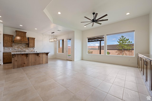 kitchen featuring backsplash, ceiling fan with notable chandelier, recessed lighting, and custom range hood