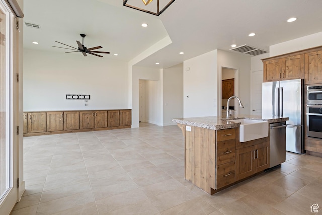kitchen with stainless steel appliances, a sink, visible vents, ceiling fan, and light stone countertops