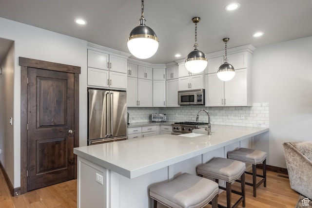 1166 W Cadence Ct, Kamas, UT 84036 - kitchen featuring a breakfast bar area, light wood finished floors, light countertops, a peninsula, and appliances with stainless steel finishes