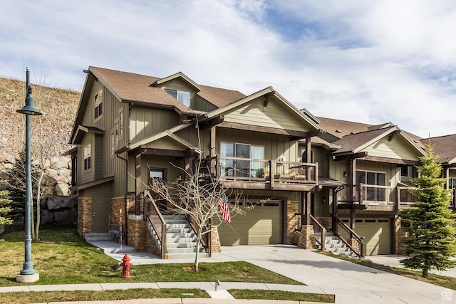 view of front of home featuring a balcony, concrete driveway, an attached garage, board and batten siding, and stone siding