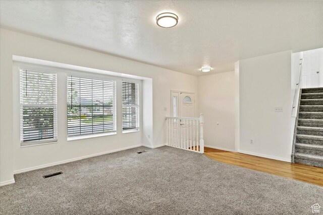 spare room with stairway, baseboards, visible vents, and carpet