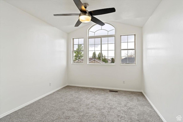 carpeted empty room featuring lofted ceiling, a ceiling fan, visible vents, and a healthy amount of sunlight
