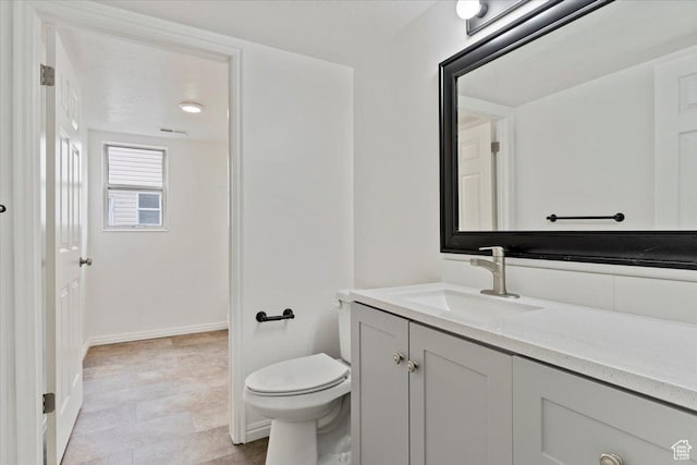 bathroom with toilet, vanity, visible vents, and baseboards