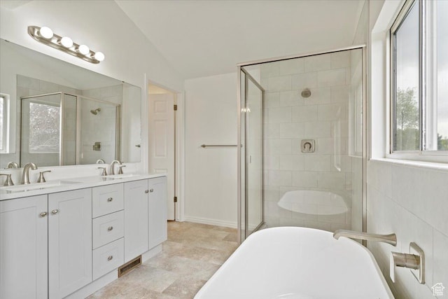 bathroom with a shower stall, vaulted ceiling, a sink, double vanity, and a freestanding bath